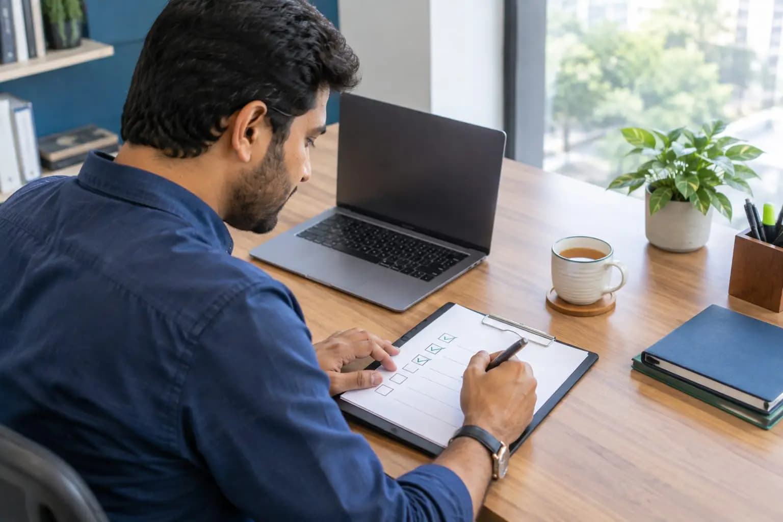 A business owner comparing options on a laptop with a checklist beside it.